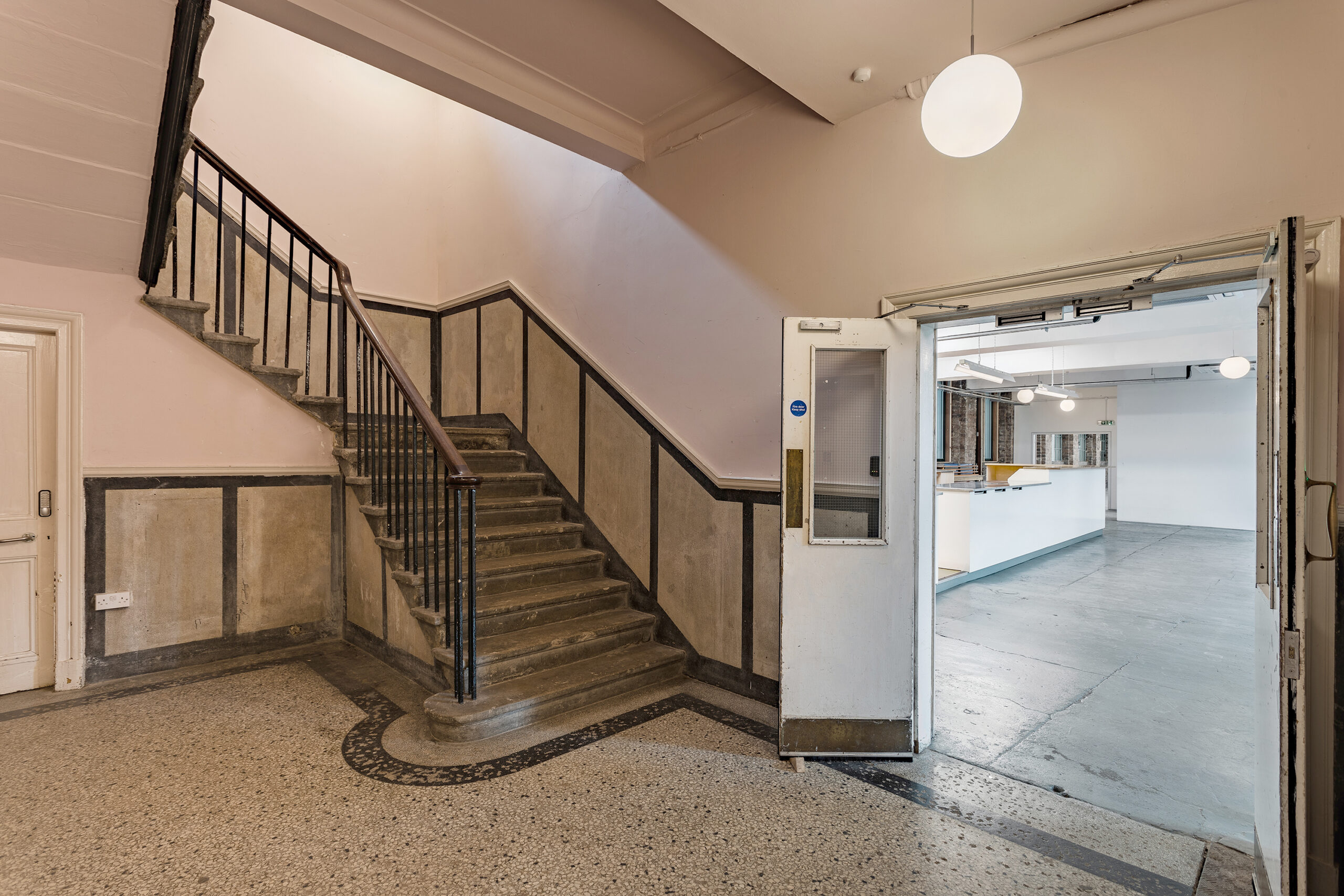 Photo of the foyer looking into the canteen. This can also be the reception area for your festival hub. There are stairs in the foreground and the kitchen and bar space in the background through a set of double doors.