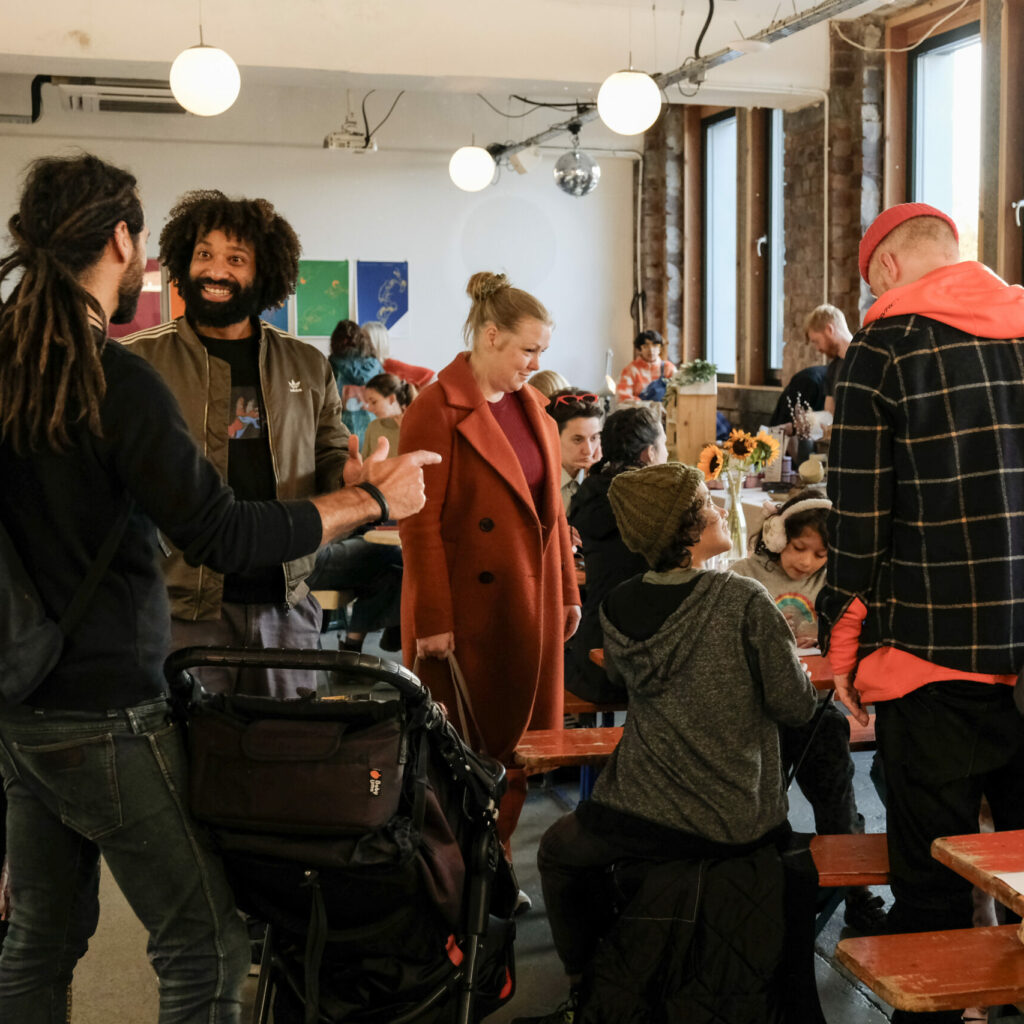 A happy group of people of all ages and dressed up in warm clothing interact with each other in Civic House Canteen