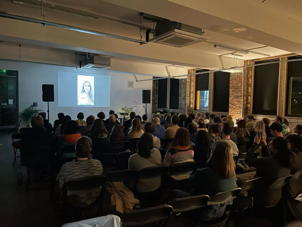 Rows of people sit in Civic House venue watching a projected screening.